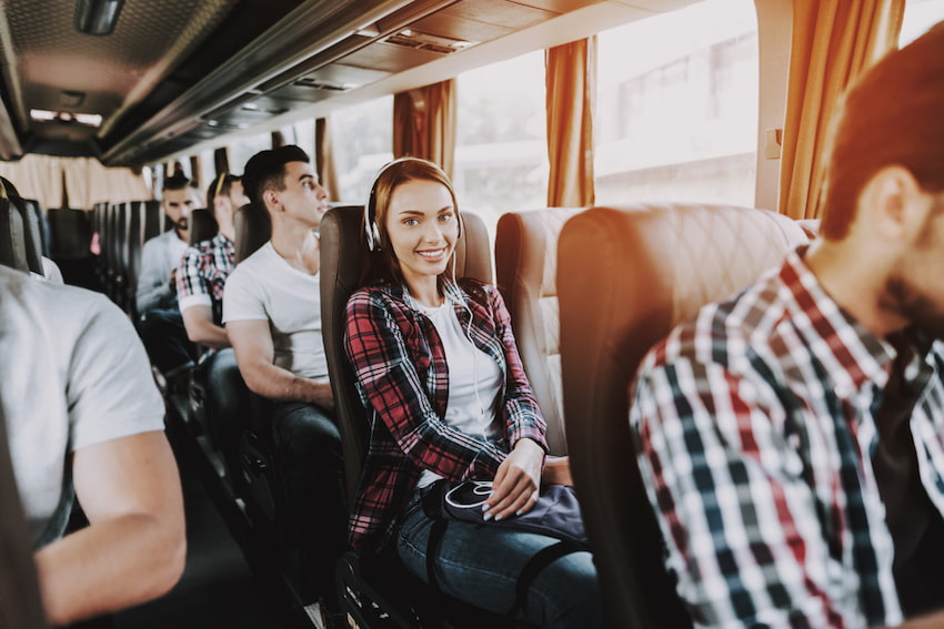 a woman sits in a charter bus seat and smiles